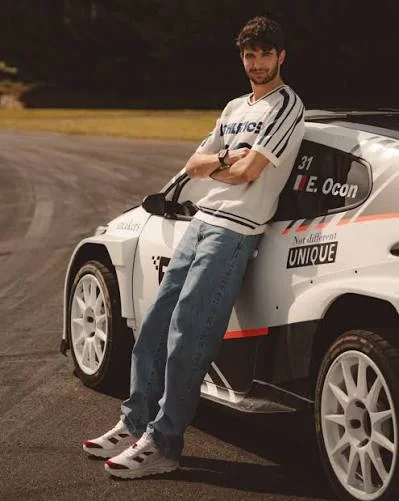 Esteban Ocon en sneakers LEVAC devant une voiture de course numéro 31